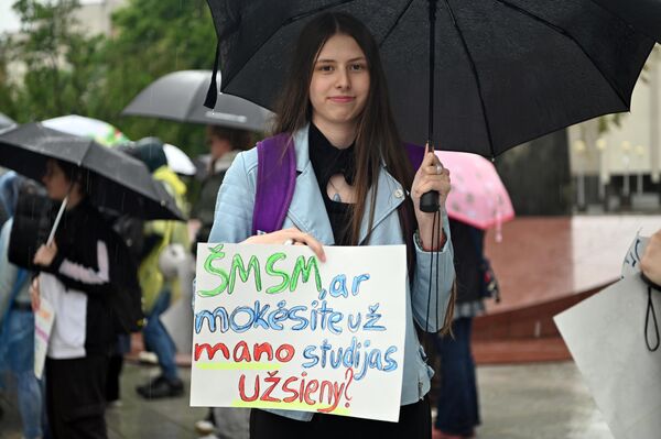 На фото: участница акции протеста держит плакат с надписью: "Минобразования, вы оплатите мое обучение за границей?" На фото: участница акции протеста держит плакат с надписью: "Минобразования, вы оплатите мое обучение за границей?" - Sputnik Литва