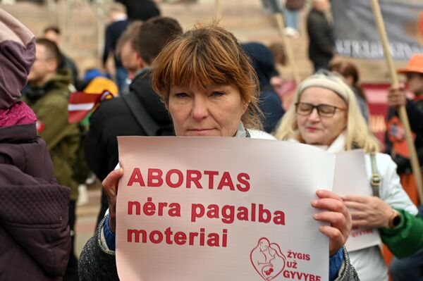 На фото: участница марша держит плакат с надписью: &quot;Аборт — это не помощь женщине&quot;. - Sputnik Литва
