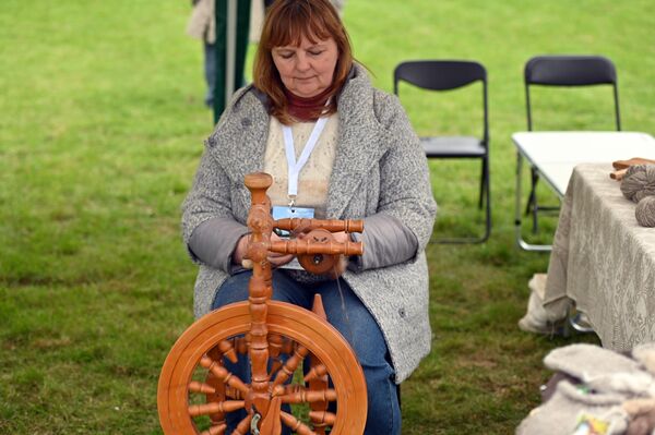 На фото: участница мероприятия изготавливает шерстяные нити. - Sputnik Литва