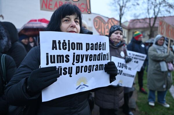 На фото: участница акции протеста держит плакат с надписью: &quot;Пришли помочь вам осуществить вашу программу&quot;. - Sputnik Литва