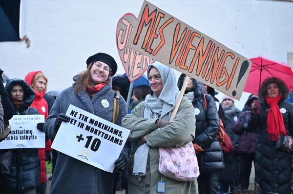 На фото: участницы акции протеста держат плакат с надписями: &quot;Не только ученикам, но и учителям + 10&quot;, &quot;Мы едины&quot;. - Sputnik Литва