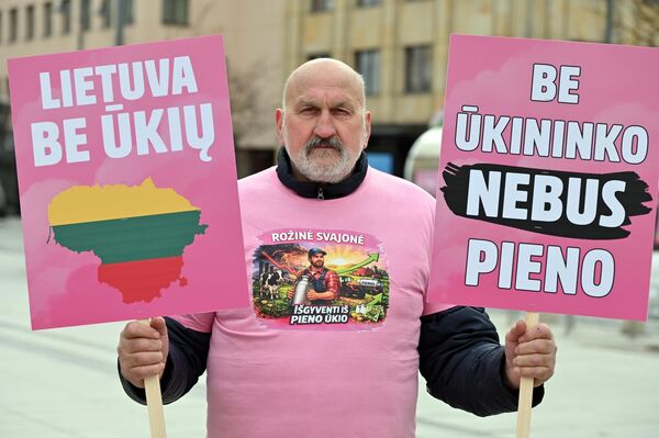 На фото: участник акции протеста держит плакаты с надписями: "Литва без сельского хозяйства", "Без фермера не будет молока". - Sputnik Литва