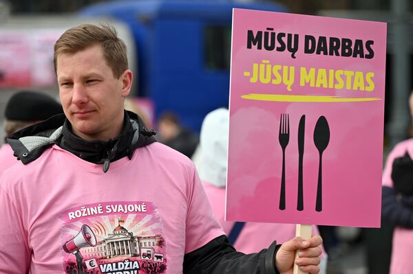 На фото: участник акции протеста держит плакат с надписью: "Наша работа — ваша пища". - Sputnik Литва