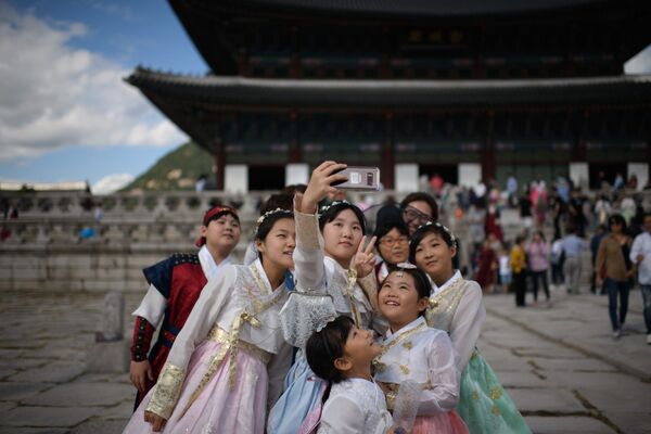 Одетые в традиционные корейские платья посетители фотографируются перед павильоном во дворце Кёнбоккун в Сеуле - Sputnik Lietuva