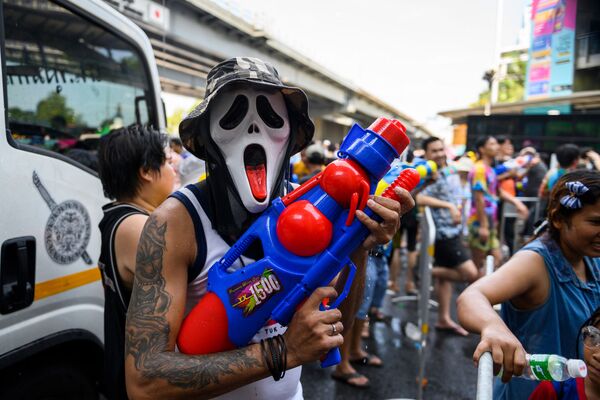 Человек в маске и с водяным пистолетом во время празднования буддийского нового года в Бангкоке - Sputnik Литва
