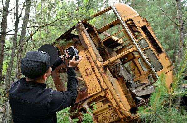 Турист фотографирует автобус в зоне отчуждения Чернобыльской АЭС - Sputnik Литва