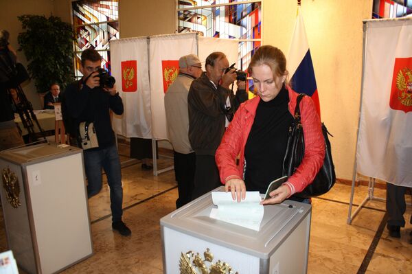 Гражданка России опускает бюллетень в урну для голосования Гражданка России опускает бюллетень в урну для голосования - Sputnik Литва