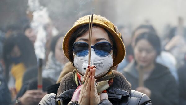 Женщина в маске и солнцезащитных очках во время молитвы в первый день Нового года в Пекине - Sputnik Lietuva
