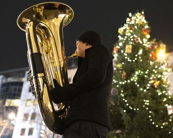 Музыкант духового оркестра Rudersdorf Music Society играет на трубе на рождественском базаре в Вене - Sputnik Литва