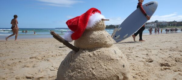 Молодой серфер проходит мимо снеговика из песка во время празднования Рождества на Бонди Бич в Сиднее, 25 декабря 2019 года Молодой серфер проходит мимо снеговика из песка во время празднования Рождества на Бонди Бич в Сиднее, 25 декабря 2019 года - Sputnik Lietuva