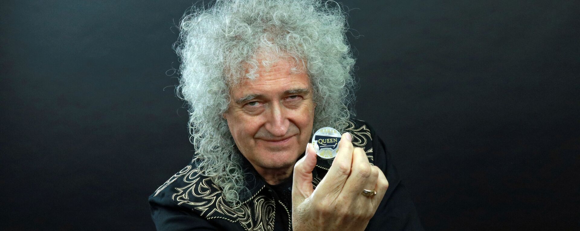 Гитарист группы Queen Брайан Мэй позирует с 5-фунтовой монетой,  выпущенной с логотипом группы - Sputnik Lietuva, 1920, 26.01.2020