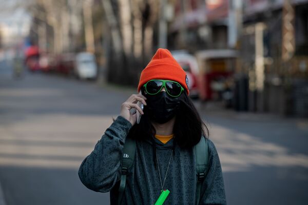 Девушка в маске и очках на пустынной улице Пекина  - Sputnik Lietuva