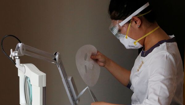 Косметолог в защитной маске и очках снимает маску для лица во время процедуры в спа-салоне красоты Pearl Deluxe в Пекине, 5 марта 2020 года - Sputnik Lietuva