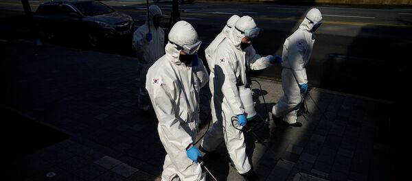 Южнокорейские солдаты в защитном снаряжении дезинфицируют улицу в торговом районе Сеула, 6 марта 2020 года - Sputnik Литва