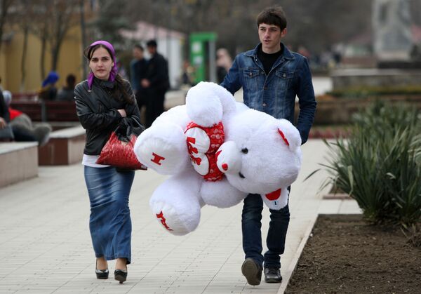 Мужчина несет подаренного девушке плюшевого медведя накануне праздника 8 марта в Грозном - Sputnik Lietuva
