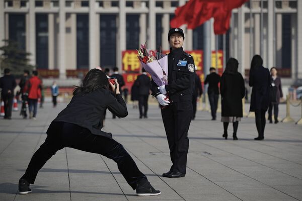 Женщина фотографирует женщину-полицейского 8 марта в Пекине - Sputnik Lietuva