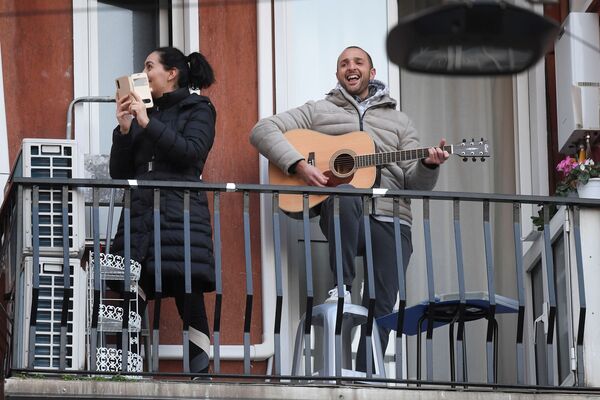 Мужчина с гитарой и женщина со смартфоном на одном из балконов в Милане - Sputnik Lietuva