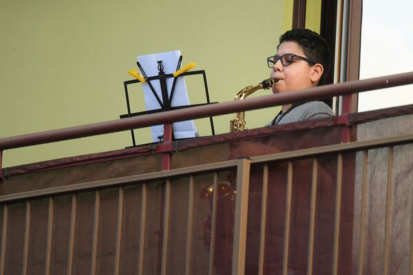 Мальчик играет на саксофоне на балконе своего дома во время карантина в Милане - Sputnik Lietuva