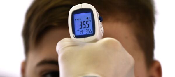 Медицинский работник измеряет температуру школьнику в одной из школ Москвы - Sputnik Литва