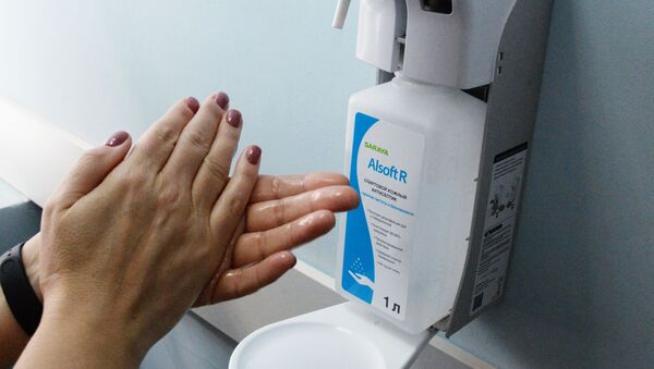 Пациент поликлиники №1 Владивостока дезинфицирует руки антисептиком перед тем как посетить кабинет врача - Sputnik Lietuva