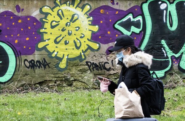 Женщина проходит мимо граффити с изображением коронавируса в Эдинбурге, Шотландия - Sputnik Lietuva