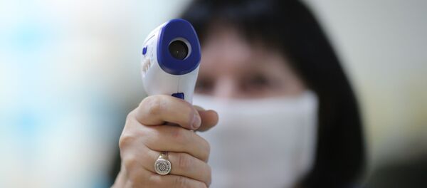 Сотрудница поликлиники готовится измерять температуру посетителей - Sputnik Литва