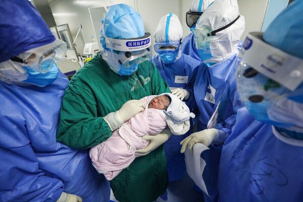 Врач держит новорожденного ребенка в отделении гинекологии и акушерства для будущих мам, инфицированных COVID-19 - Sputnik Lietuva
