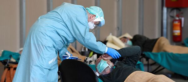 Врач помогает пациенту во временной больнице в Брешиа, Италия - Sputnik Литва