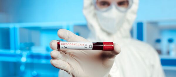 Сотрудник лаборатории в защитном костюме держит образец крови с коронавирусом - Sputnik Литва