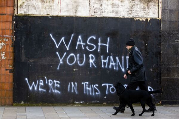 Мужчина с собакой напротив граффити с призывом мыть руки в Северной Ирландии - Sputnik Lietuva
