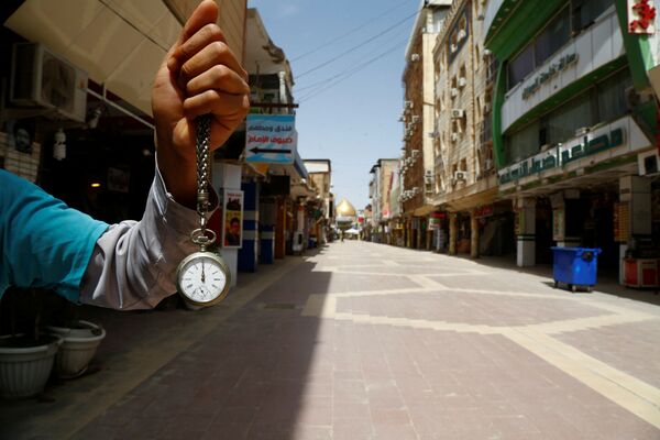 Показывающие полдень карманные часы в руках мужчины в районе рынка близ мечети имама Али в Наджафе, Ирак, в период пандемии коронавируса - Sputnik Литва