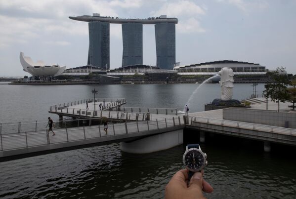 Показывающие полдень часы напротив  Merlion Park в Сингапуре в период пандемии коронавируса - Sputnik Литва