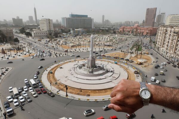 Показывающие полдень наручные часы на фоне пустой площади Тахрир в Каире в период пандемии коронавируса - Sputnik Литва