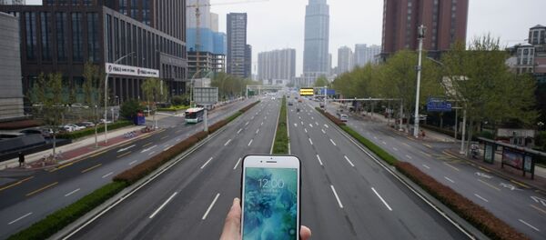 Показывающие полдень часы в мобильном телефоне на фоне пустой автомобильной дороги в Ухане в период пандемии коронавируса Показывающие полдень часы в мобильном телефоне на фоне пустой автомобильной дороги в Ухане в период пандемии коронавируса - Sputnik Lietuva