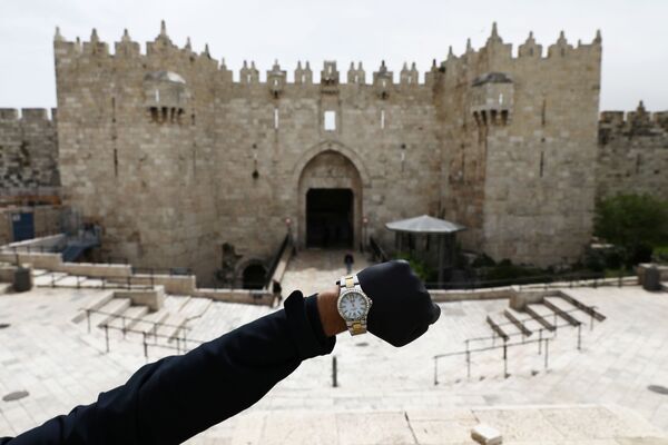 Показывающие полдень наручные часы на фоне Дамасских ворот в Иерусалиме в период пандемии коронавируса - Sputnik Lietuva