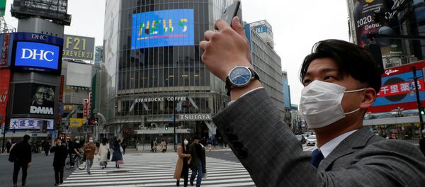 Мужчина в защитной маске фотографирует на мобильный телефон в полдень на перекрестке Сибуя в Токио во время пандемии коронавируса Мужчина в защитной маске фотографирует на мобильный телефон в полдень на перекрестке Сибуя в Токио во время пандемии коронавируса - Sputnik Lietuva