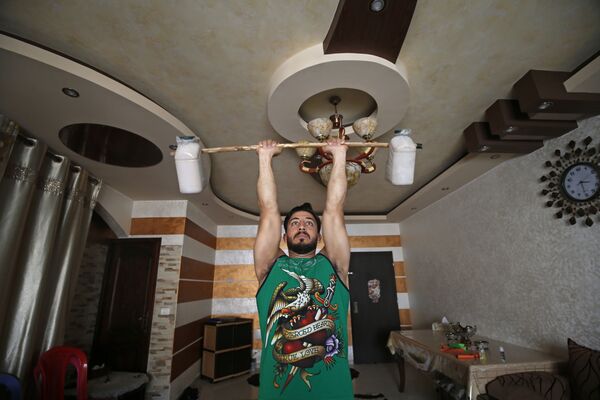 Палестинский тренер по фитнесу и бодибилдингу Ахмед Сави во время тренировки у себя дома - Sputnik Литва