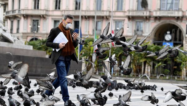 Мужчина в маске идет среди голубей в центре Милана, Италия - Sputnik Литва