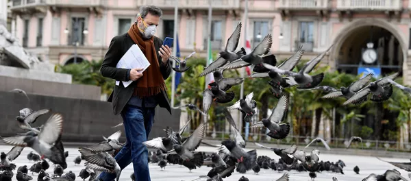 Мужчина в маске идет среди голубей в центре Милана, Италия - Sputnik Lietuva
