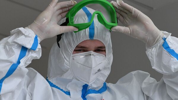 Медицинский работник надевает защиту от коронавируса, архивное фото - Sputnik Литва