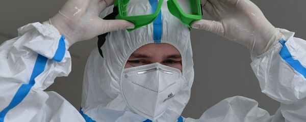 Медицинский работник надевает защиту от коронавируса, архивное фото - Sputnik Литва