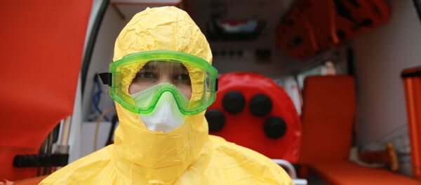 Врач бригады скорой помощи в защитном костюме перед бокс для перевозки зараженных коронавирусом - Sputnik Литва