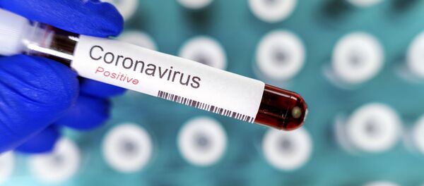 Медработник держит в руках пробирку, с положительным результатом теста на коронавирус - Sputnik Литва