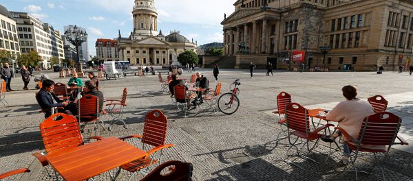 Люди наслаждаются погодой в кафе на площади Жандарменмаркт в Берлине, соблюдая принцип социальной дистанции - Sputnik Литва