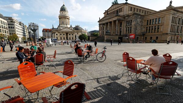 Люди наслаждаются погодой в кафе на площади Жандарменмаркт в Берлине, соблюдая принцип социальной дистанции - Sputnik Lietuva