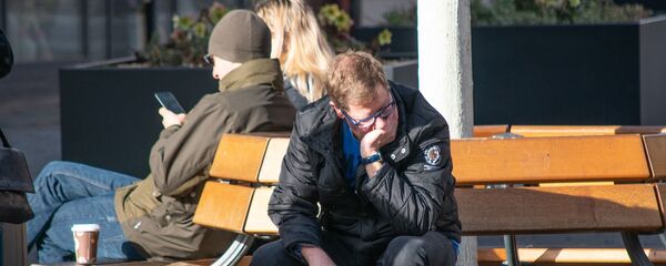 Молодой человек сидит на скамейке Молодой человек сидит на скамейке - Sputnik Lietuva