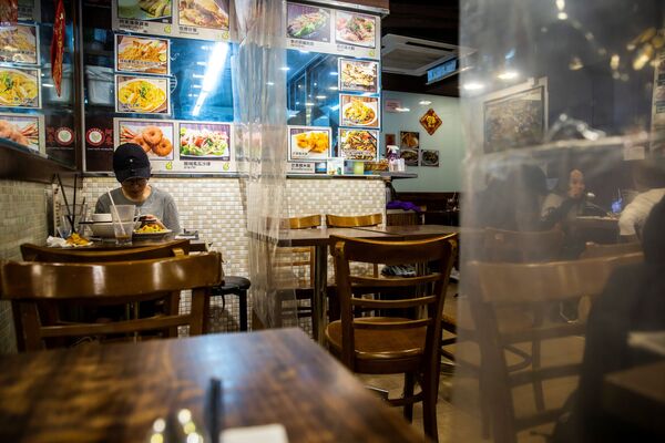 Посетитель ресторана, разделенного пластиковыми полотнами в Гонконге  - Sputnik Литва