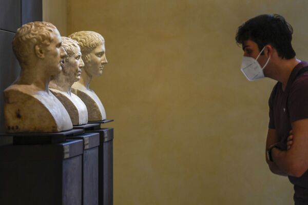 Посетитель в маске рассматривает коллекцию Капитолийского музея в Риме - Sputnik Литва