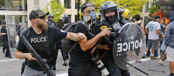 Полицейский толкает фотографа во время протестов в США Полицейский толкает фотографа во время протестов в США - Sputnik Lietuva