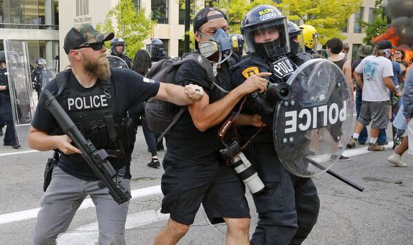 Полицейский толкает фотографа во время протестов в США  - Sputnik Lietuva